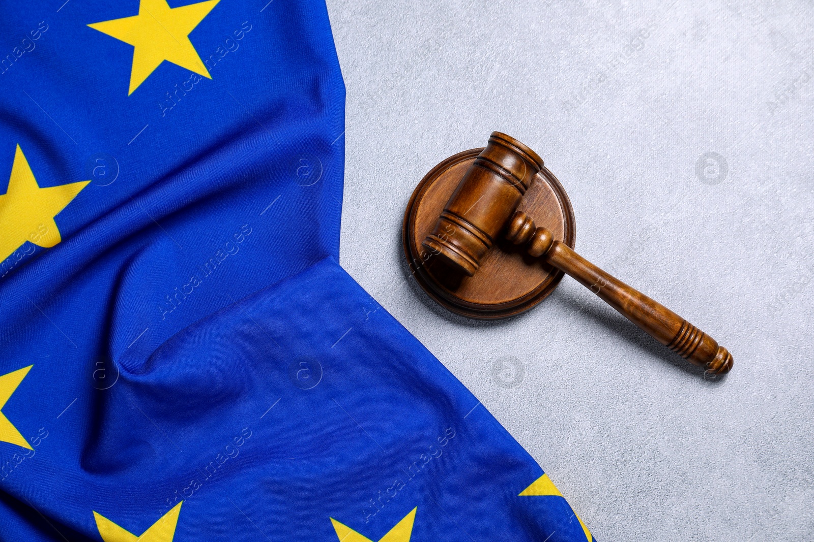 Photo of Judge's gavel and flag of European Union on light grey table, top view