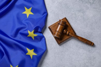 Photo of Judge's gavel and flag of European Union on light grey table, top view