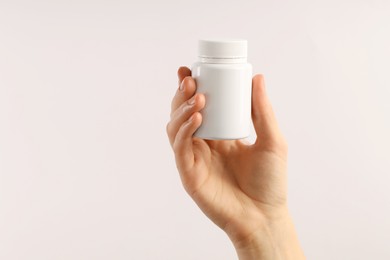 Photo of Woman holding medical bottle with pills on white background, closeup. Space for text