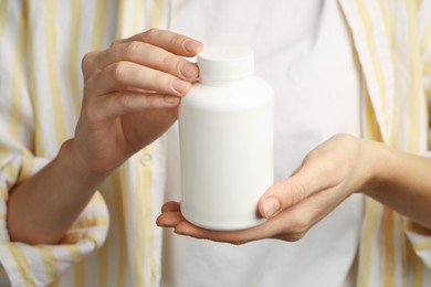 Photo of Woman holding medical bottle with pills, closeup