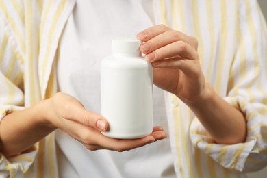 Photo of Woman holding medical bottle with pills, closeup