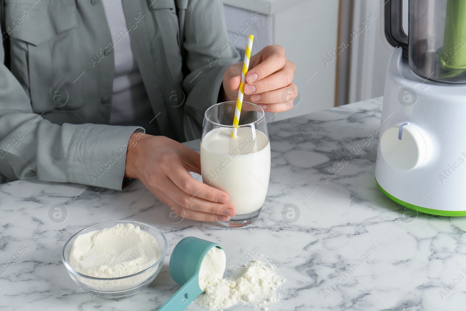 Photo of Woman with glass of protein cocktail at white marble table, closeup