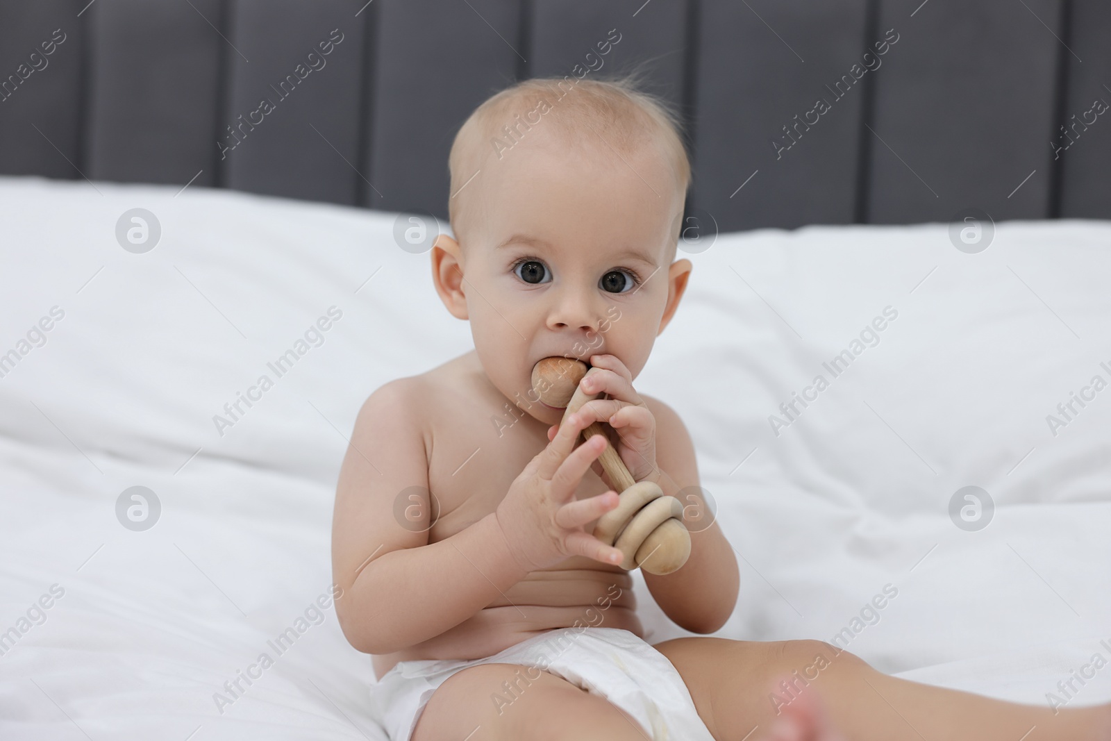 Photo of Cute little baby with rattle on bed indoors