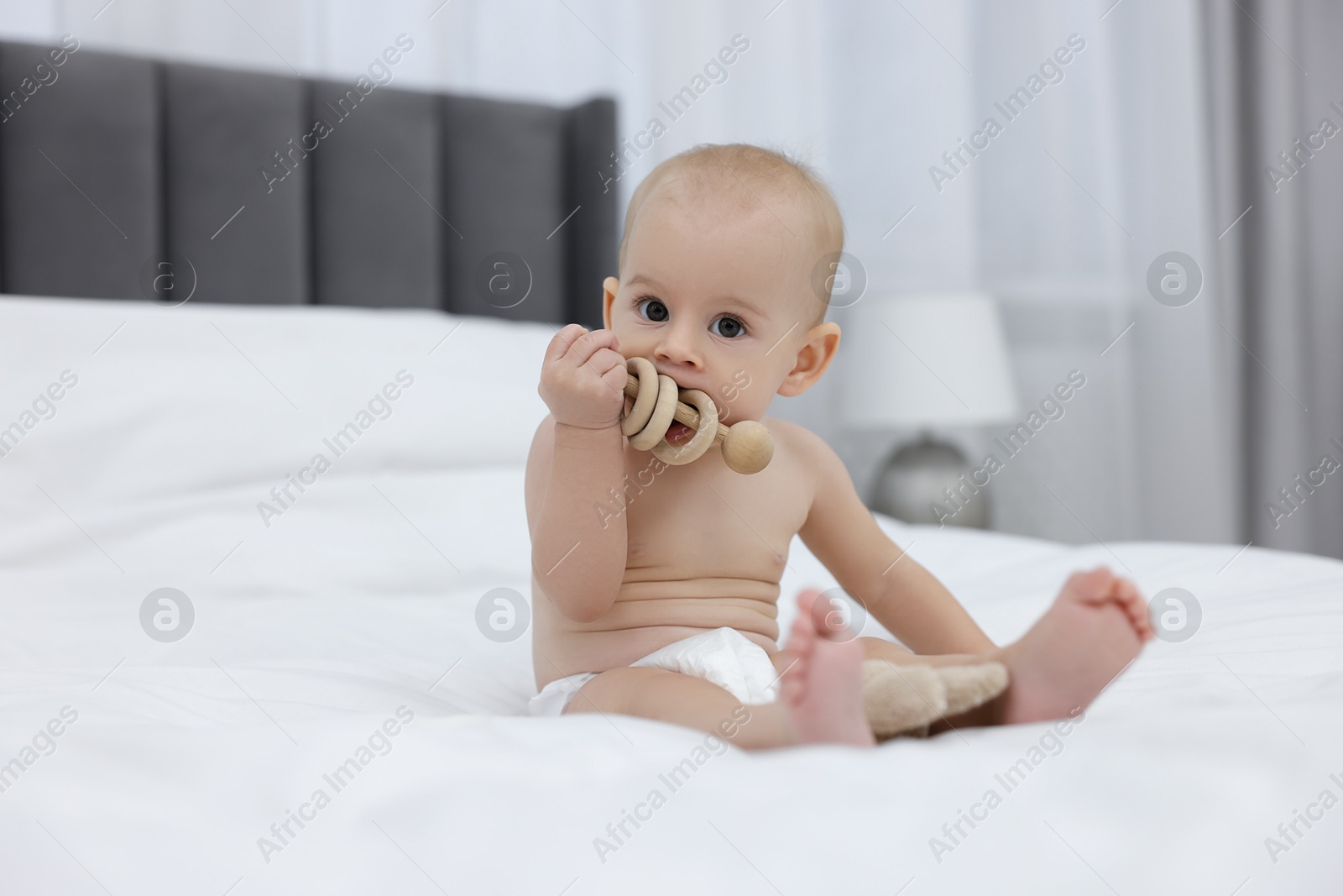 Photo of Cute little baby with rattle on bed indoors