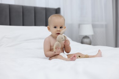 Photo of Cute little baby with rattle on bed indoors