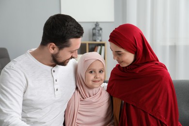 Photo of Happy Muslim family sitting on sofa at home