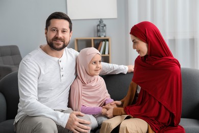 Photo of Happy Muslim family sitting on sofa at home