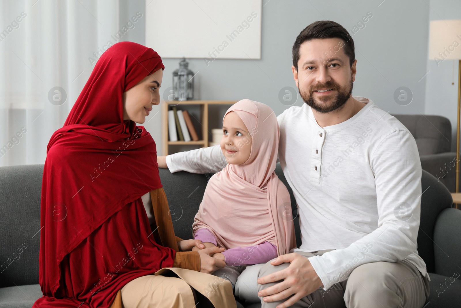 Photo of Happy Muslim family sitting on sofa at home