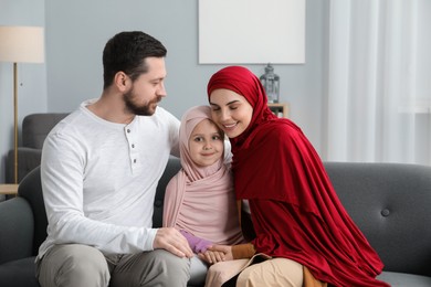 Photo of Happy Muslim family sitting on sofa at home