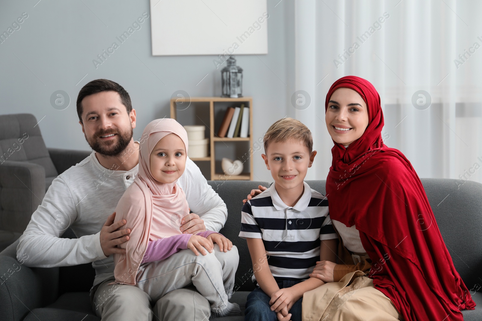 Photo of Happy Muslim family sitting on sofa at home