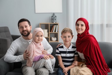 Happy Muslim family sitting on sofa at home