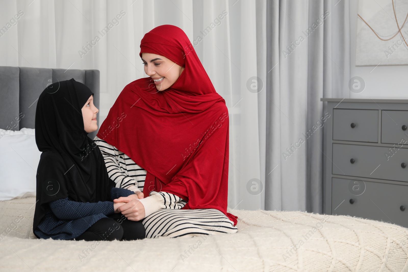 Photo of Muslim woman and her daughter spending time together at home, space for text