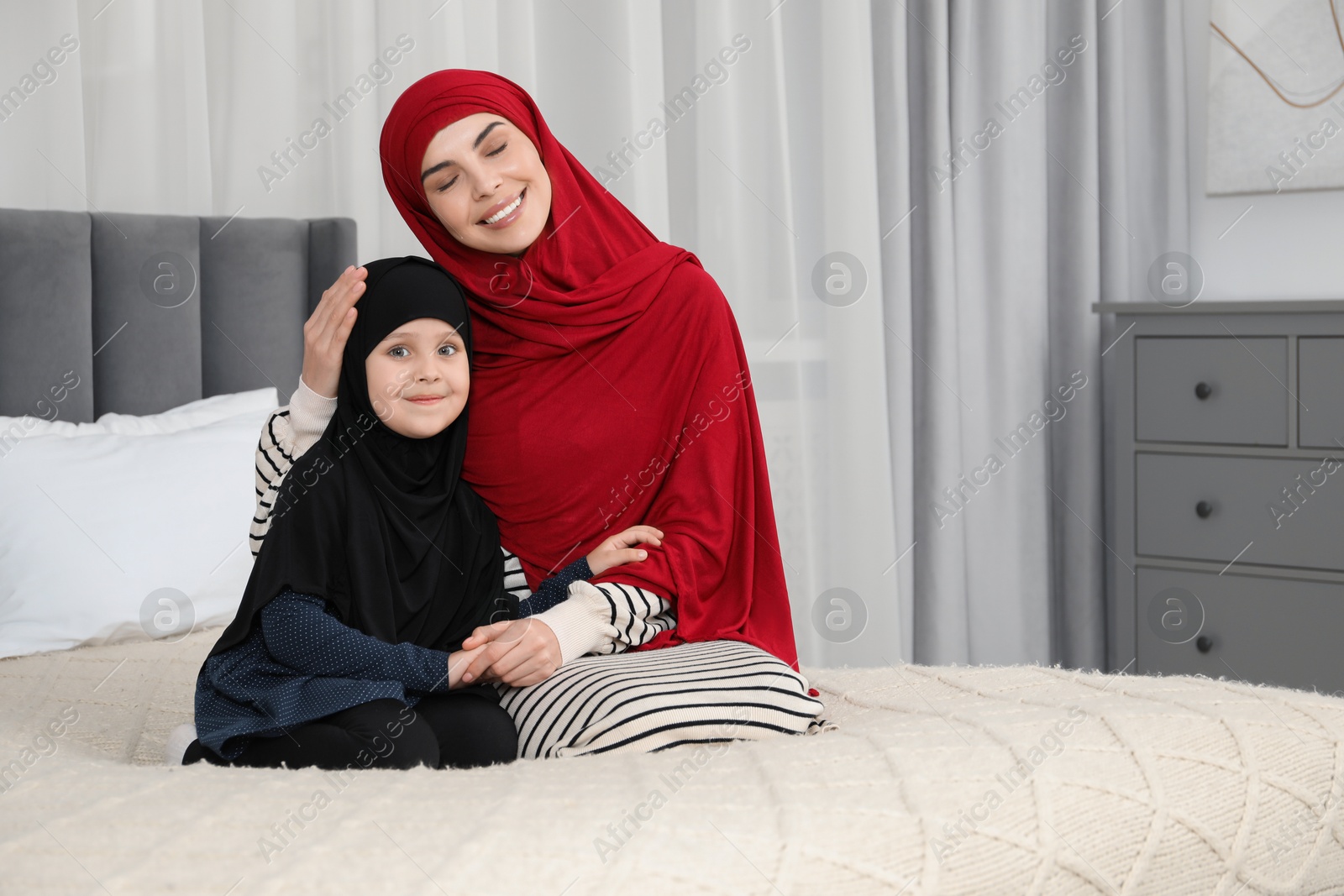 Photo of Muslim woman and her daughter spending time together at home, space for text