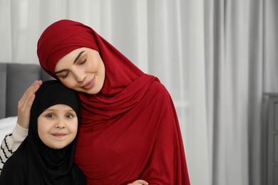 Photo of Muslim woman and her daughter spending time together at home, space for text