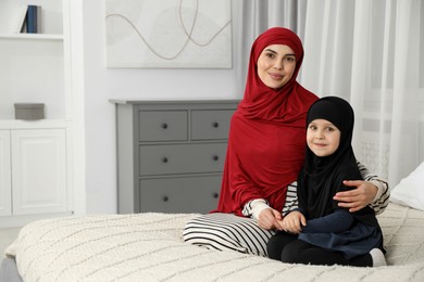 Photo of Muslim woman and her daughter spending time together at home, space for text