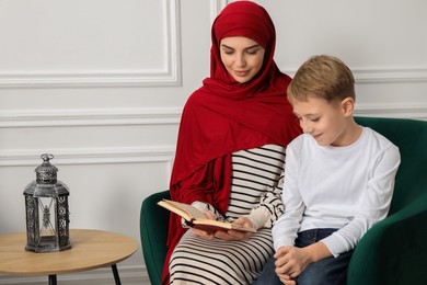 Photo of Muslim woman and her son reading Quran at home