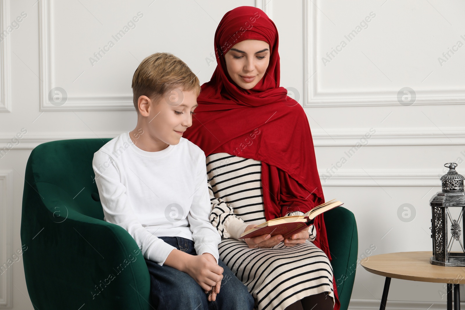 Photo of Muslim woman and her son reading Quran at home