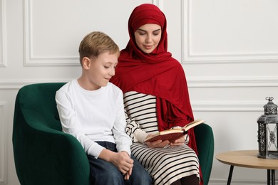 Photo of Muslim woman and her son reading Quran at home