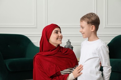 Photo of Muslim woman and her son spending time together at home