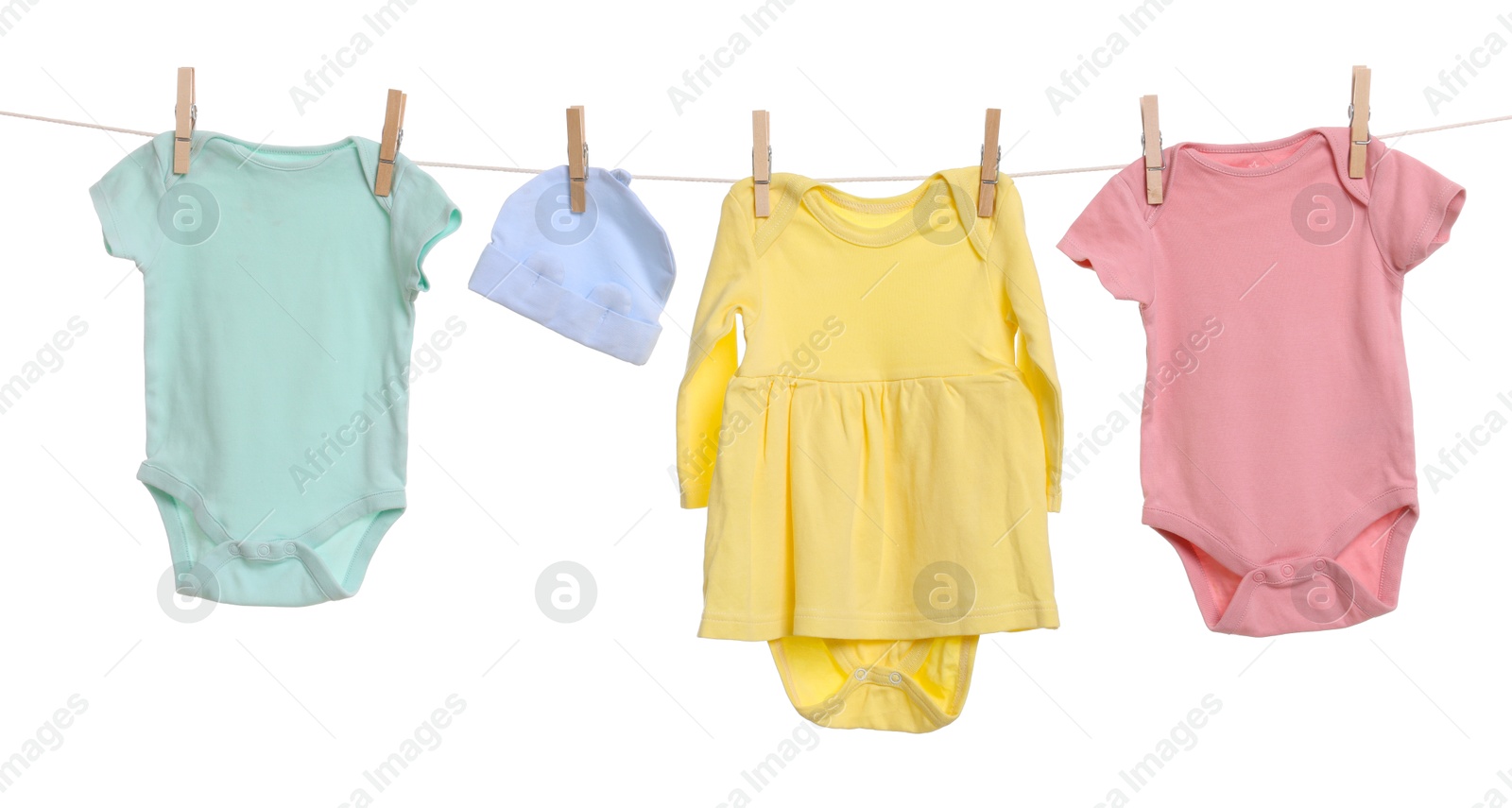 Photo of Different baby clothes drying on laundry line against white background