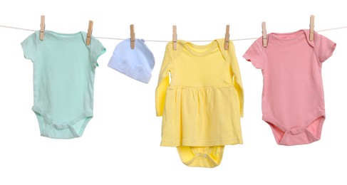 Photo of Different baby clothes drying on laundry line against white background