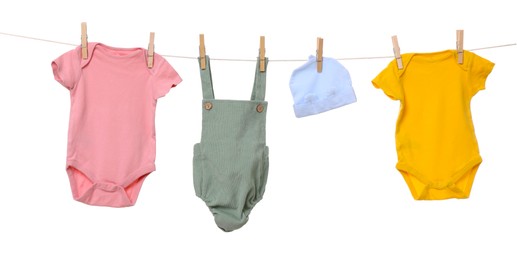 Photo of Different baby clothes drying on laundry line against white background