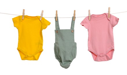 Photo of Different baby clothes drying on laundry line against white background