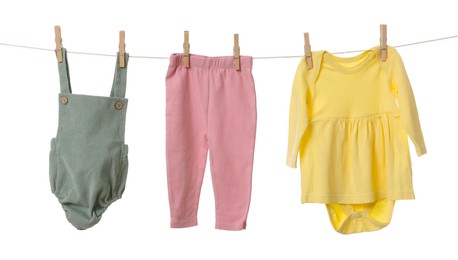 Photo of Different baby clothes drying on laundry line against white background