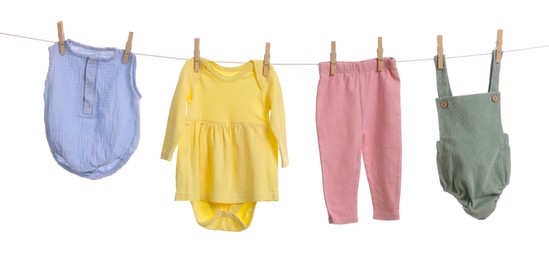 Photo of Different baby clothes drying on laundry line against white background