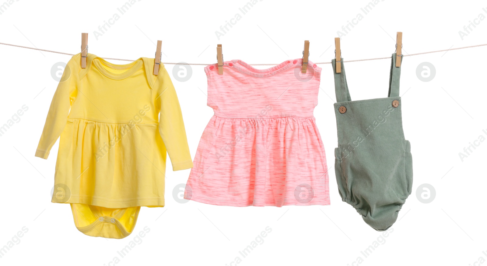 Photo of Different baby clothes drying on laundry line against white background