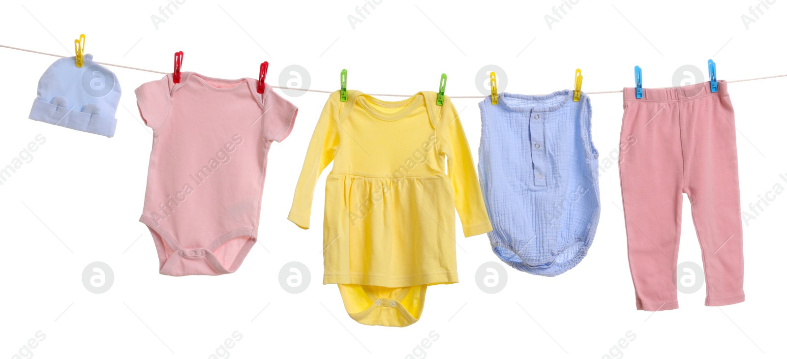 Photo of Different baby clothes drying on laundry line against white background