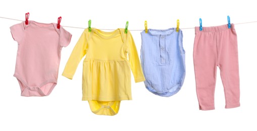 Photo of Different baby clothes drying on laundry line against white background