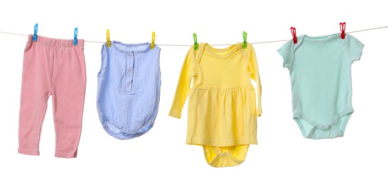 Photo of Different baby clothes drying on laundry line against white background