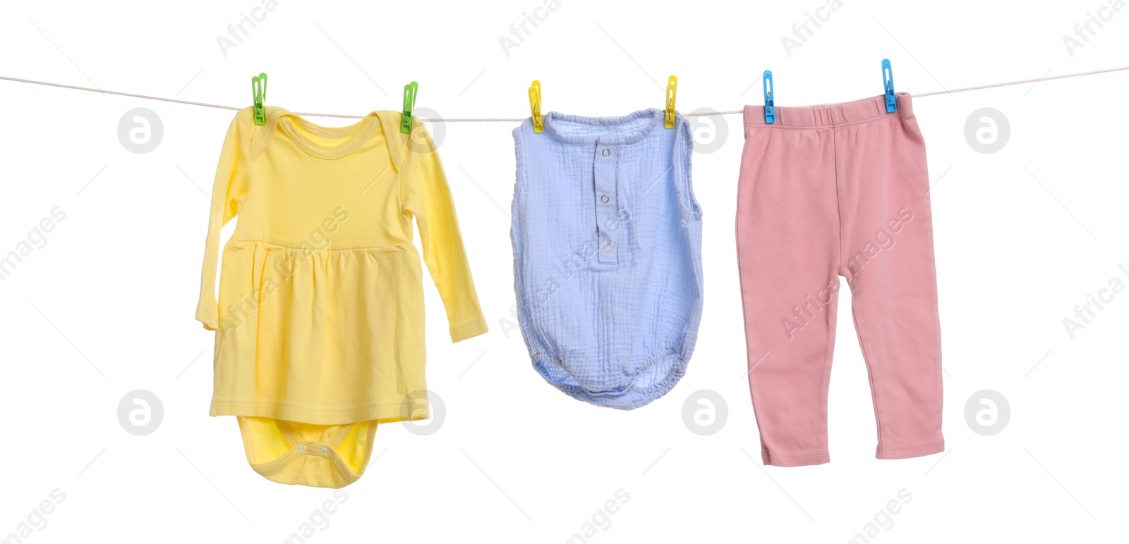 Photo of Different baby clothes drying on laundry line against white background