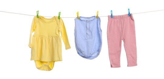 Photo of Different baby clothes drying on laundry line against white background