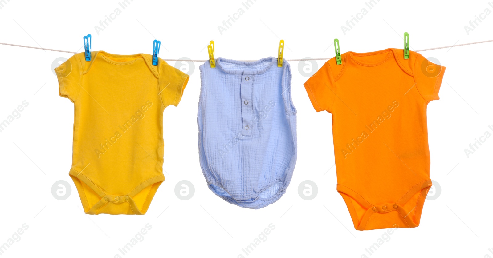 Photo of Different baby clothes drying on laundry line against white background