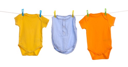 Photo of Different baby clothes drying on laundry line against white background