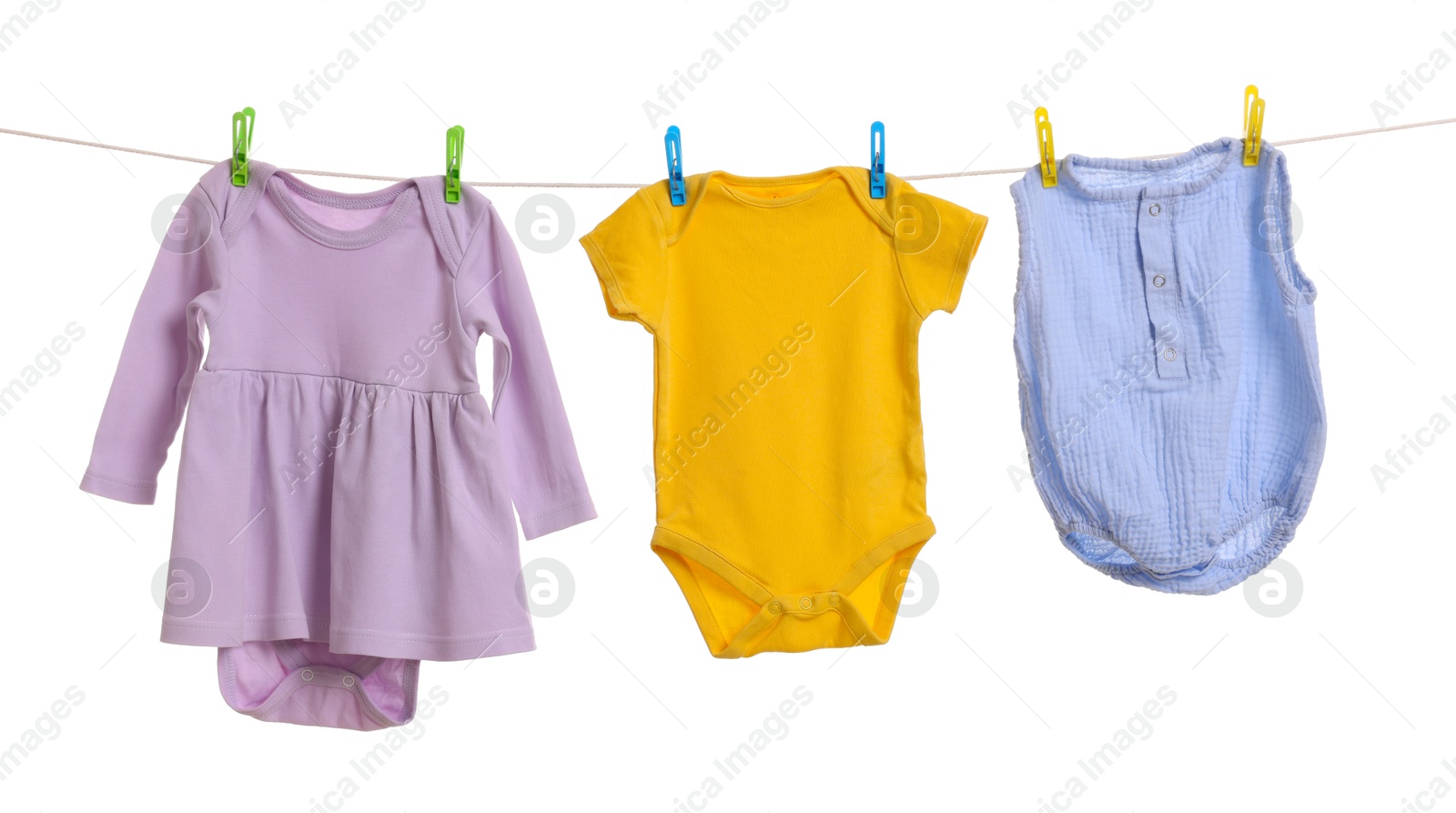 Photo of Different baby clothes drying on laundry line against white background