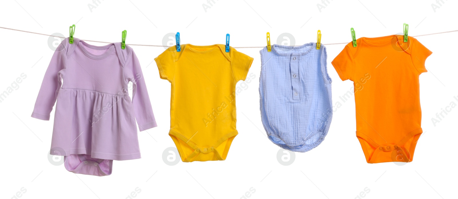 Photo of Different baby clothes drying on laundry line against white background