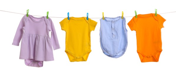 Different baby clothes drying on laundry line against white background