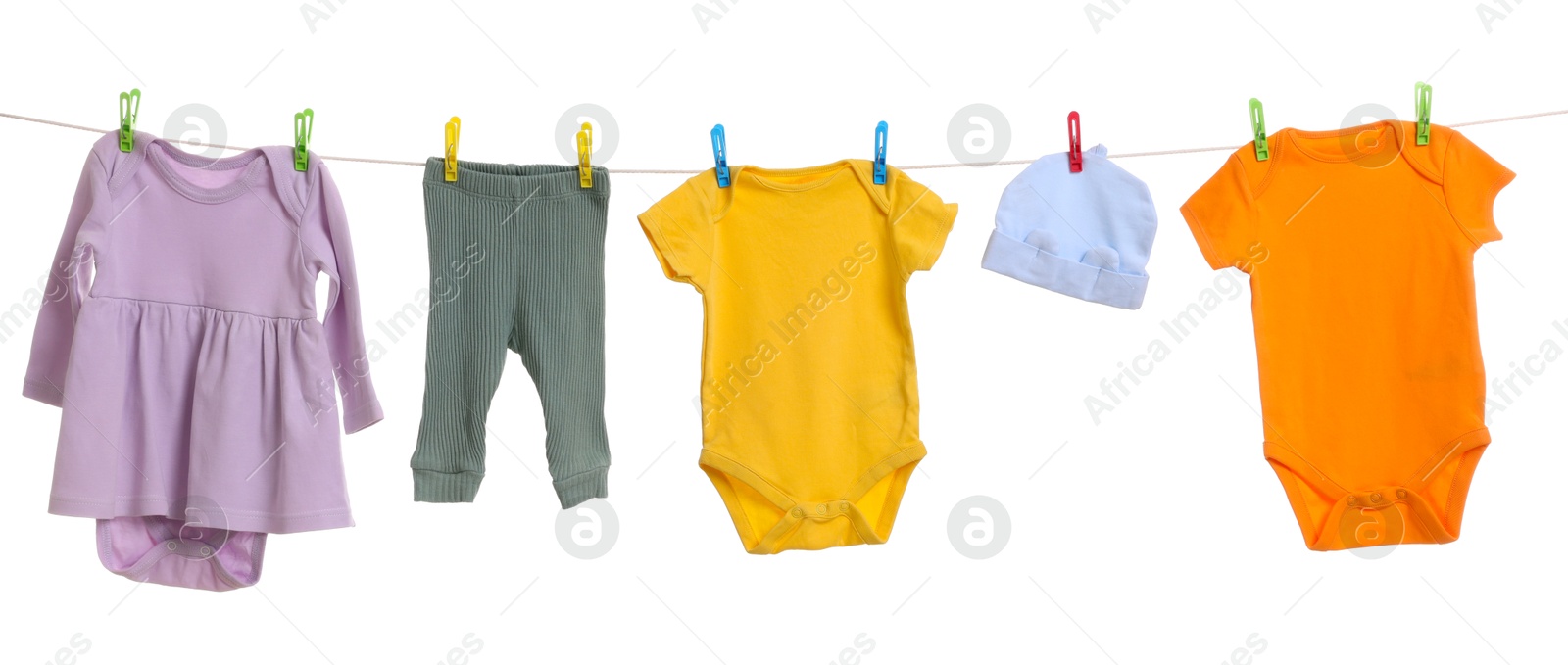 Photo of Different baby clothes drying on laundry line against white background