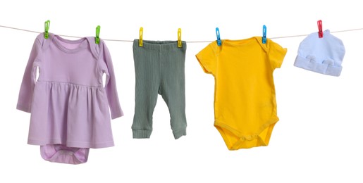 Photo of Different baby clothes drying on laundry line against white background