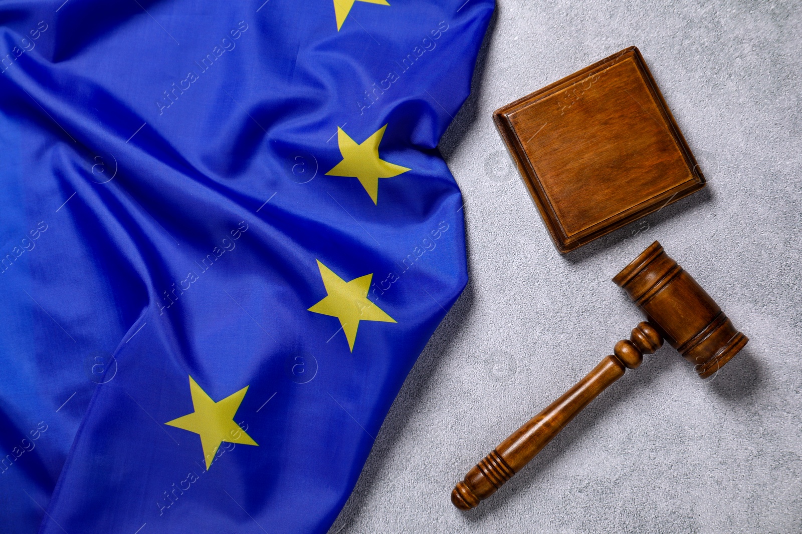 Photo of Judge's gavel and flag of European Union on light grey table, top view