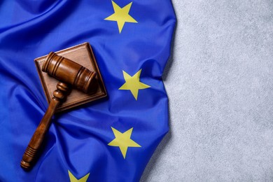 Photo of Judge's gavel and flag of European Union on light grey table, top view. Space for text