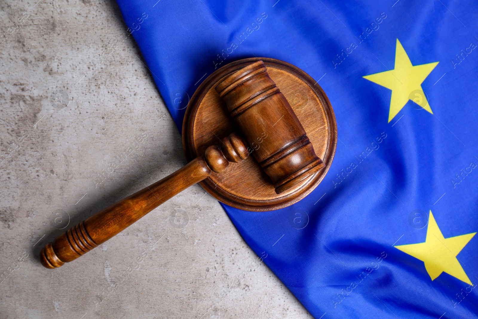 Photo of Judge's gavel and flag of European Union on grey table, top view