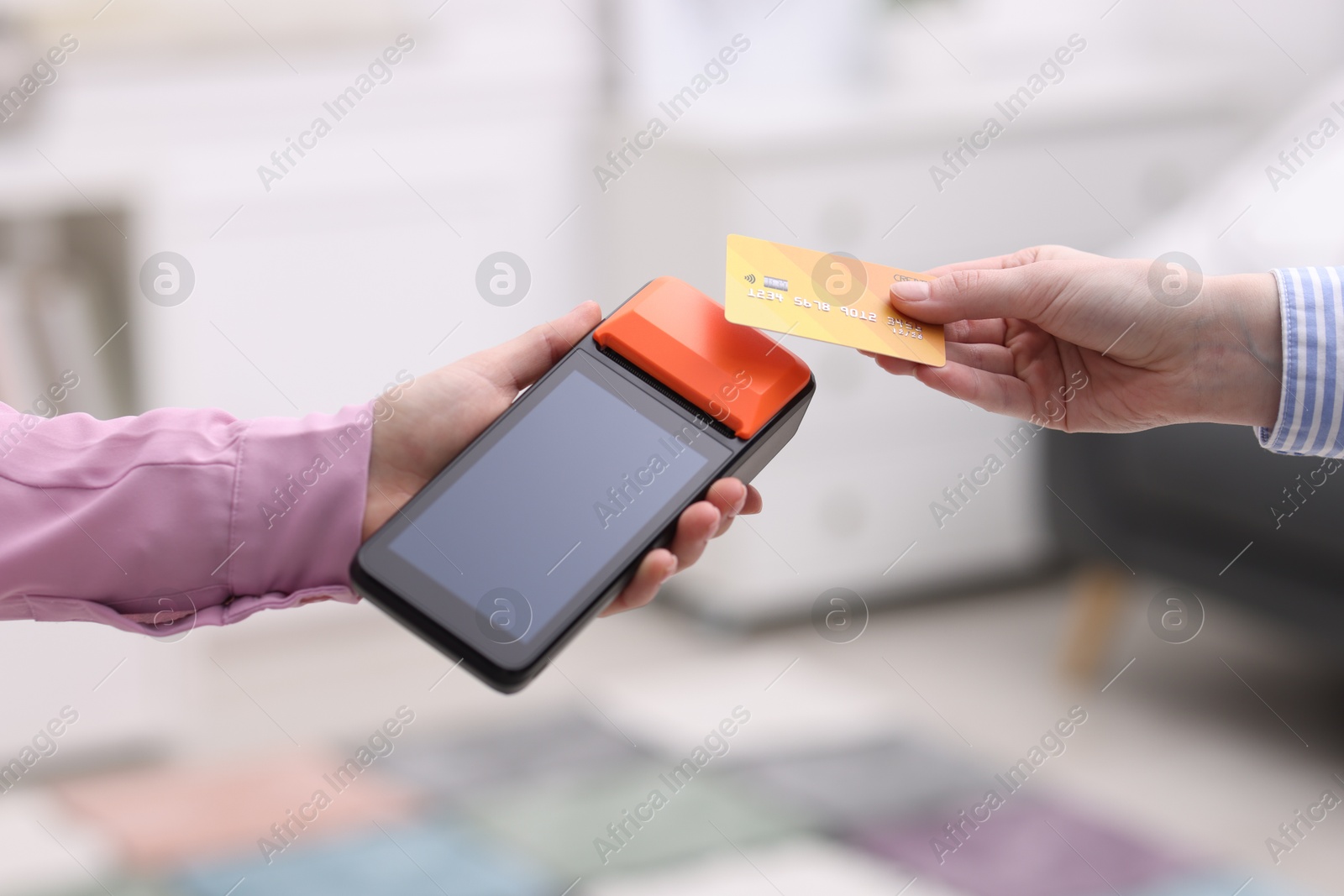 Photo of Woman paying with credit card via terminal against blurred background, closeup