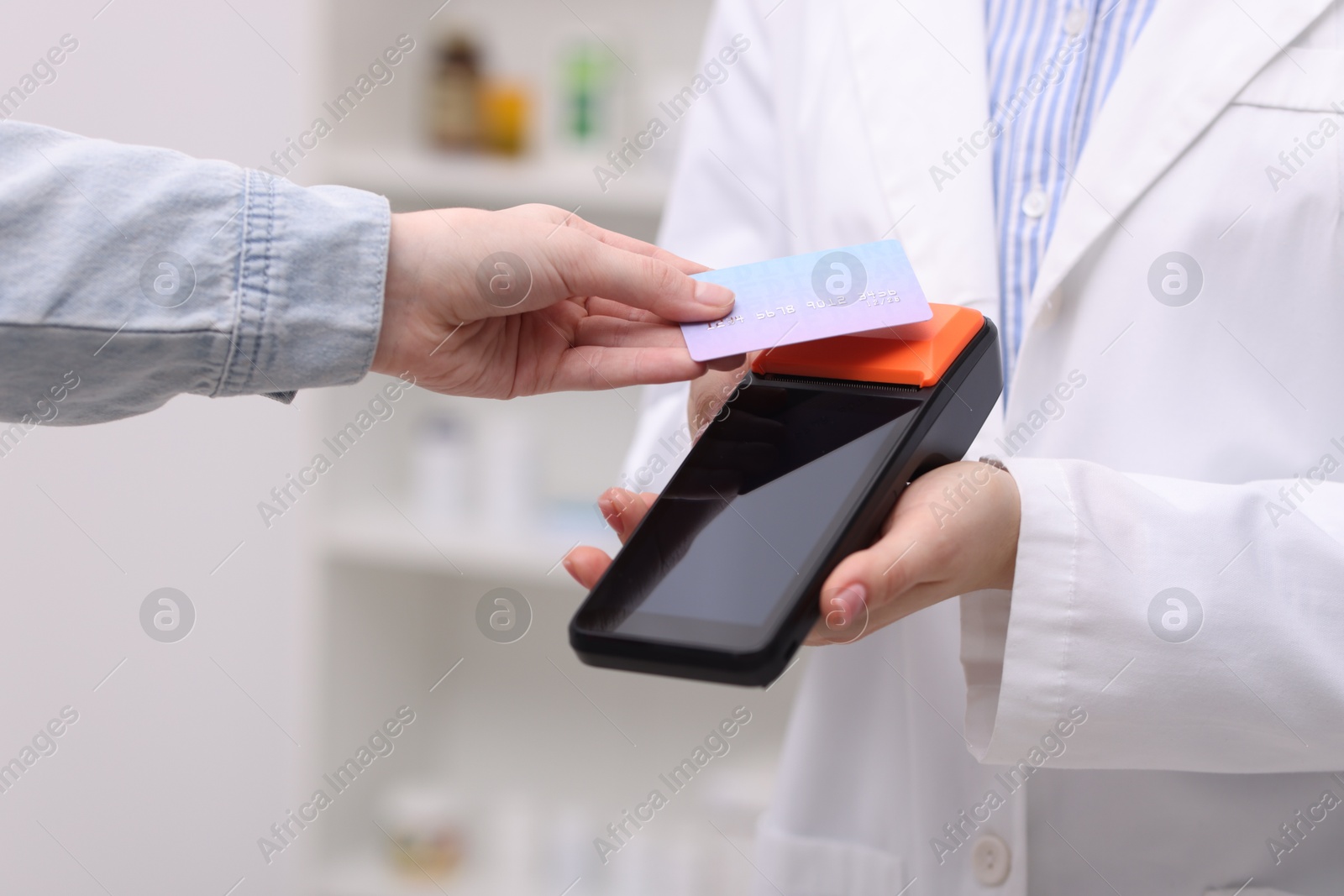 Photo of Woman paying with credit card via terminal against blurred background, closeup