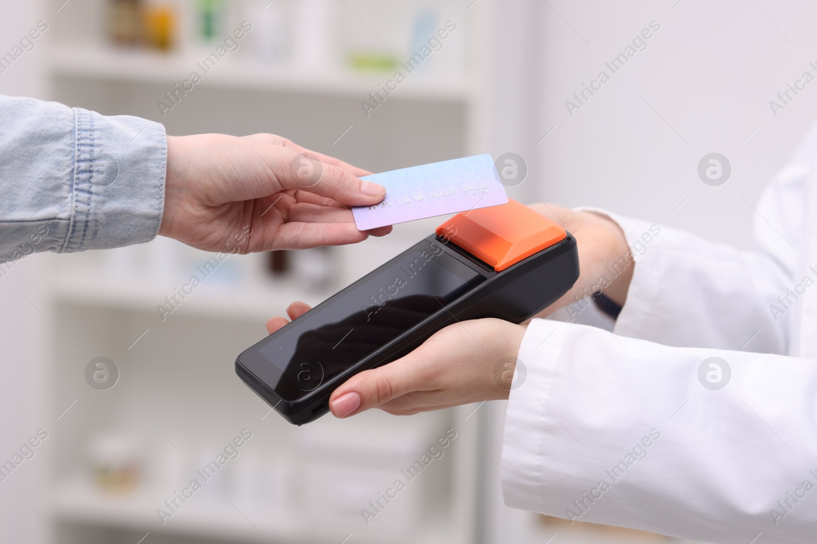 Photo of Woman paying with credit card via terminal against blurred background, closeup