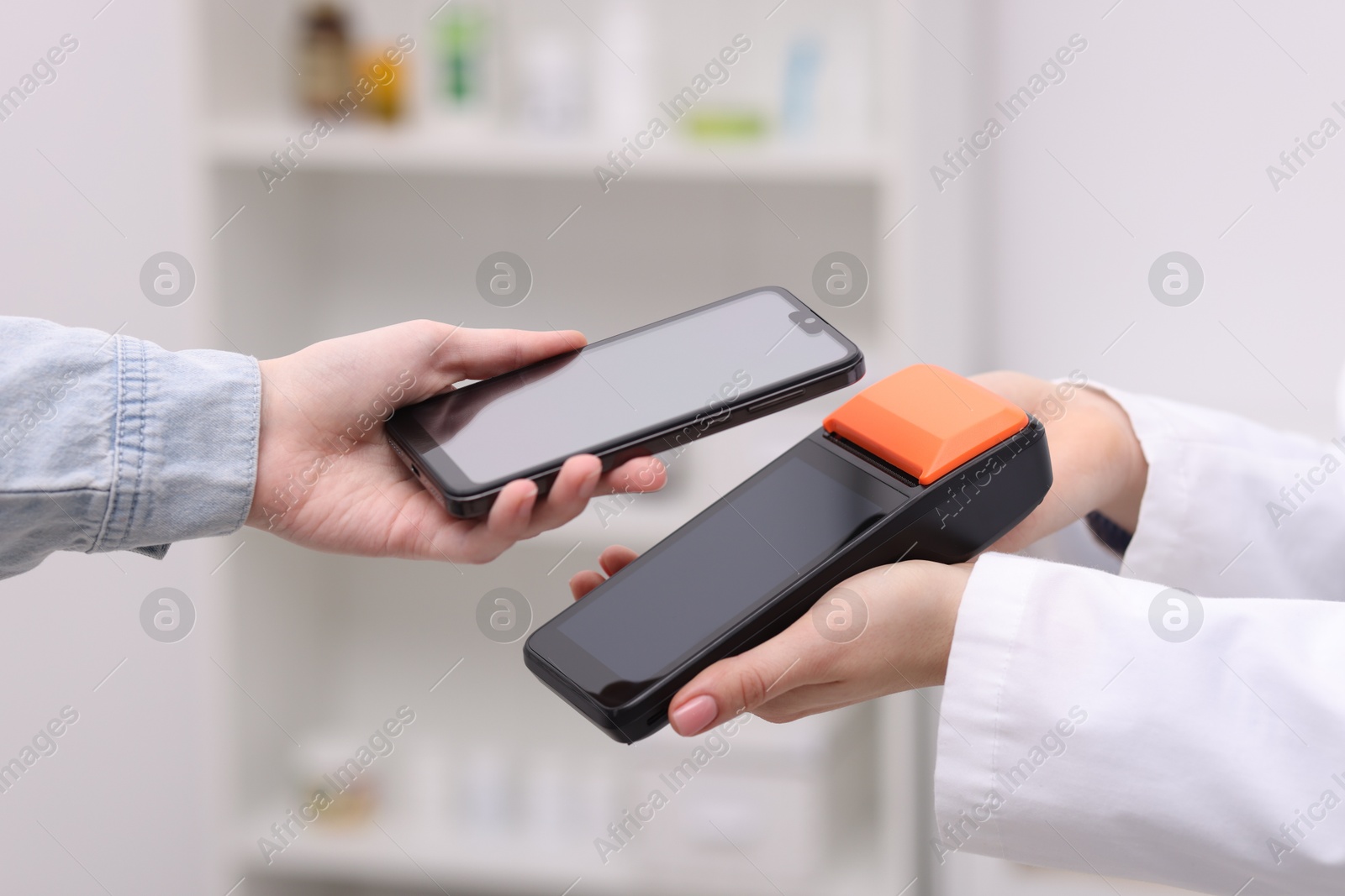 Photo of Woman paying with smartphone via terminal against blurred background, closeup