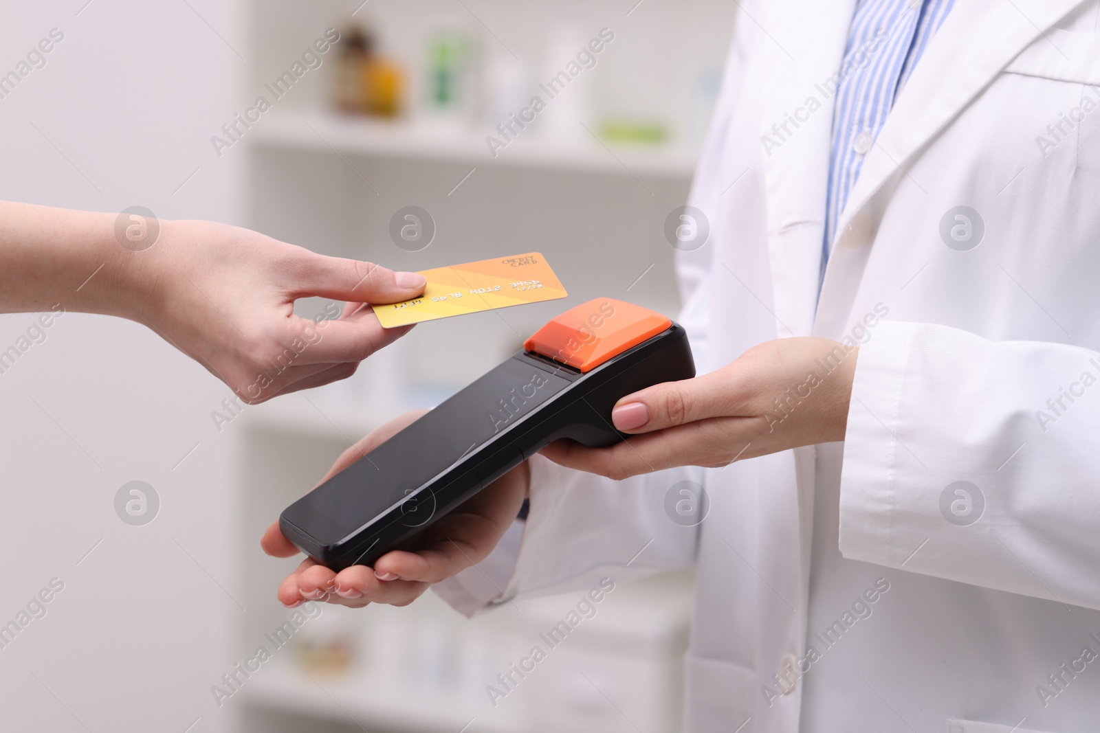 Photo of Woman paying with credit card via terminal against blurred background, closeup